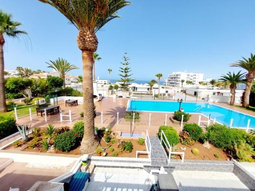 a resort with a swimming pool and palm trees at FIRST LINE Villa Floor Studio Apartment with amazing sea view Air Conditioned just 50m from the beach in Adeje
