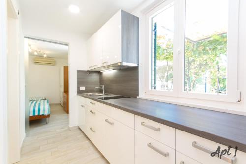 a kitchen with white cabinets and a sink and a window at Apartments Kolenc in Portorož