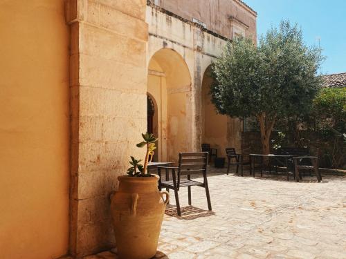 a patio with tables and chairs and a potted plant at Palazzo Gambuzza in Ispica