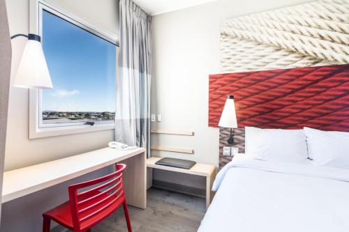 a bedroom with a bed and a desk and a window at ibis Copiapo in Copiapó