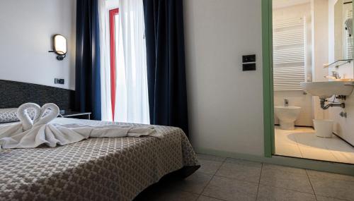 a bedroom with a bed and a bathroom with a sink at Hotel Nobel in Rimini