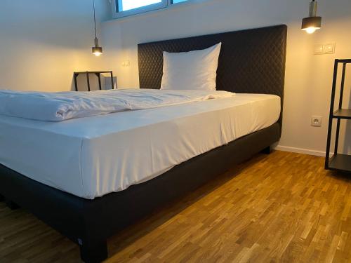 a large bed in a room with a wooden floor at City Apartments Kaiserslautern in Kaiserslautern