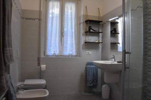 a bathroom with a sink and a toilet and a window at La Resilienza, apartment with view, Carate Urio in Carate Urio
