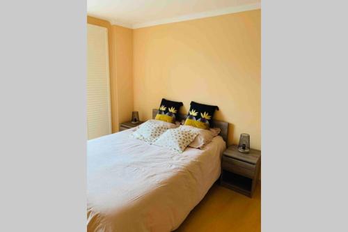 une chambre avec un grand lit blanc avec des oreillers dans l'établissement La roseraie de L arguenon, appartement charmant centre ville, à Jugon Les Lacs