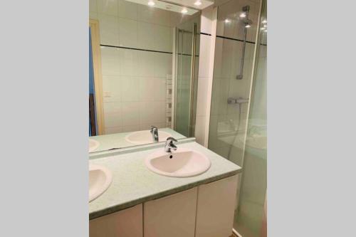 a bathroom with two sinks and a glass shower at La roseraie de L arguenon, appartement charmant centre ville in Jugon Les Lacs