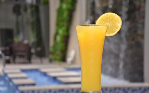 a glass of orange juice with an orange slice at Midan Hotel & Suites Al Aziziya in Makkah
