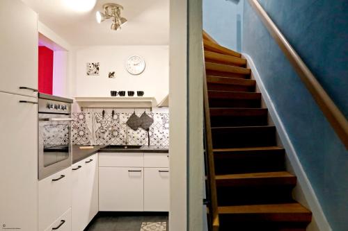 a kitchen with white cabinets and a staircase at Gemütliches Stadthaus im Herzen der Altstadt in Bad Dürkheim