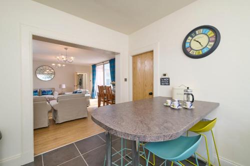 a kitchen and living room with a table and a clock at Monkland Cottage in Nairn
