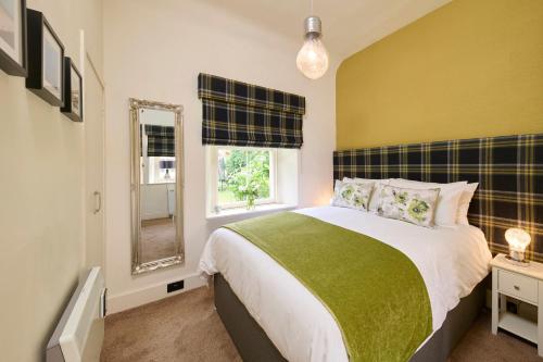 1 dormitorio con cama, ventana y espejo en Monkland Cottage, en Nairn