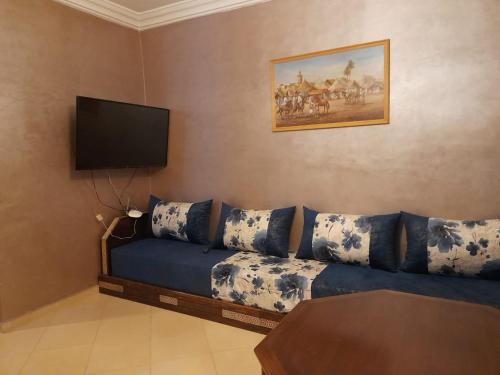 een woonkamer met een blauwe bank en een flatscreen-tv bij دار الضيافة Dar Diafa Essalam in Agadir