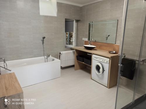 a bathroom with a tub and a sink and a washing machine at Maison de village 6/9 prs in Sauveterre-de-Rouergue