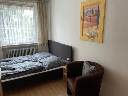 a bedroom with a bed and a chair and a window at Schöne einfache Ferienwohnung mitten in Oldenburg in Oldenburg