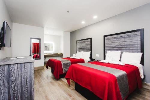 two beds in a room with red and gray sheets at Palace Inn and Suites Baytown in Baytown
