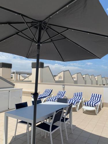 a table and chairs with an umbrella on a roof at Apartamento con solarium Villa Amalia in Torrevieja