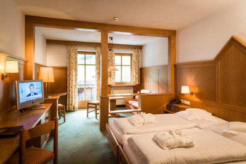 Pokój hotelowy z 2 łóżkami i biurkiem w obiekcie Posthotel Rössle w mieście Gaschurn