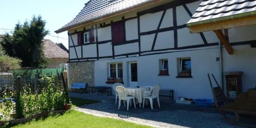a white and black house with a table and chairs at Gîte Les Sabots de Paille, Alsace Haut-Rhin in Ballersdorf