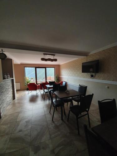 a dining room with tables and chairs and a large window at Nikolo Inn in Stepantsminda