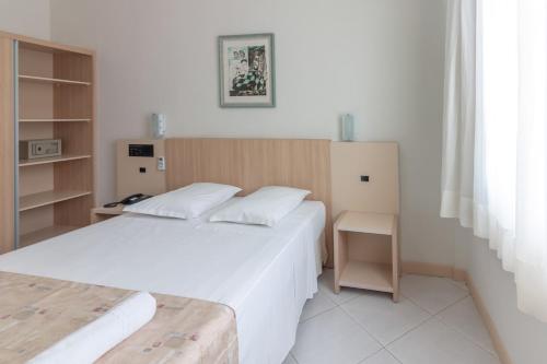 a small bedroom with two beds and a desk at Hotel Sagres Praia in Balneário Camboriú