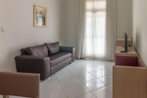 a living room with a couch and a television at Hotel Sagres Praia in Balneário Camboriú