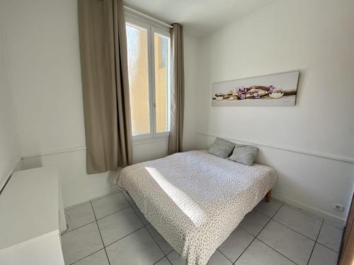 een witte kamer met een bed en een raam bij les meublés du soleil in Menton