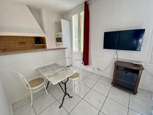 een keuken met een tafel en stoelen en een televisie bij les meublés du soleil in Menton