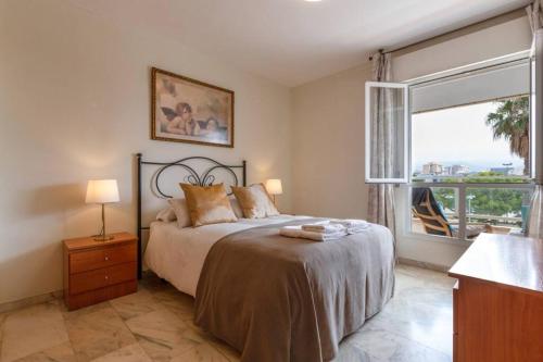 a bedroom with a bed and a large window at Playa Huelin Apartamento in Málaga