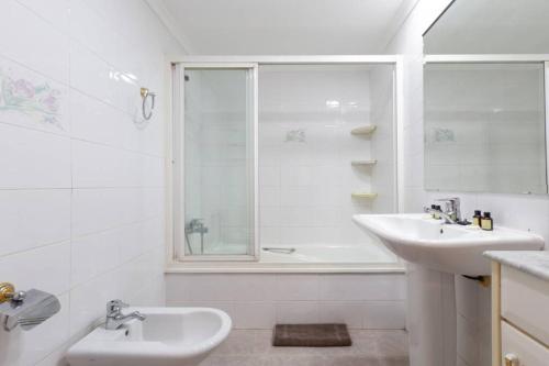 a white bathroom with a sink and a shower at Playa Huelin Apartamento in Málaga
