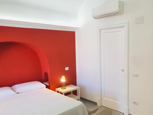 a bedroom with a white bed and a red wall at La Palladiana - Immobilevante in Ponza