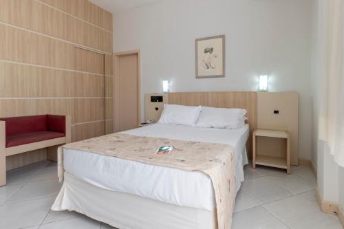 a bedroom with a large bed and a red chair at Hotel Sagres Praia in Balneário Camboriú