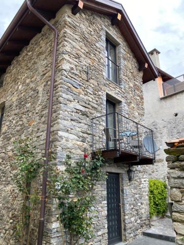un edificio in pietra con balcone e fiori di Rustico San Giorgio: Losone a Losone