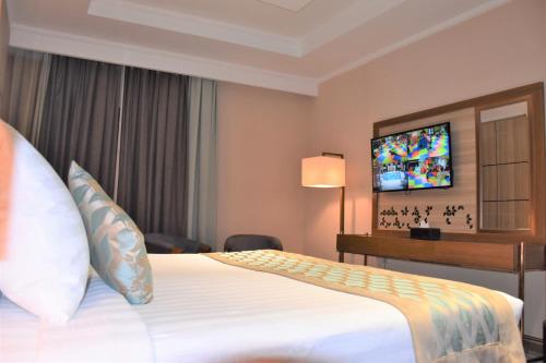 a hotel room with a bed and a flat screen tv at Midan Hotel & Suites Al Aziziya in Makkah