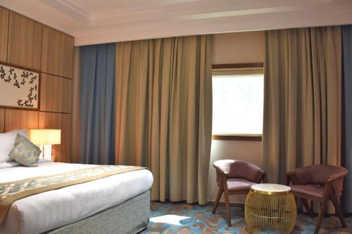 a hotel room with a bed and a chair at Midan Hotel & Suites Al Aziziya in Makkah