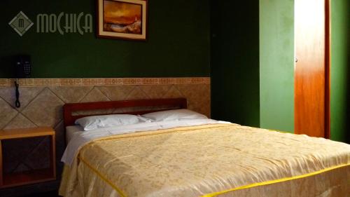 a bed in a room with a green wall at Hostal Residencial Mochica in Lima