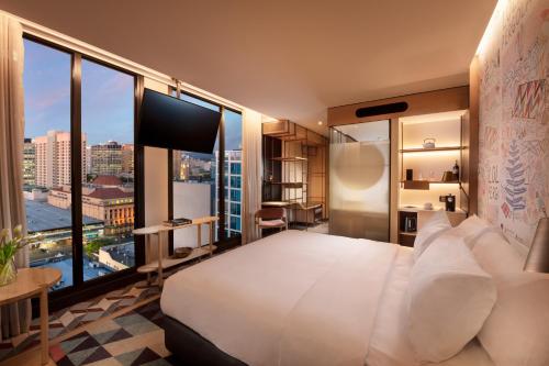 a bedroom with a large white bed and a large window at Hotel Indigo Adelaide Markets by IHG in Adelaide