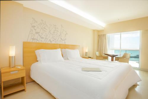 a bedroom with a large white bed with a book on it at Golden Tulip Macaé in Macaé