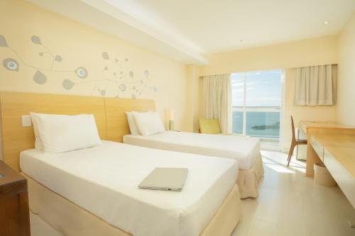um quarto de hotel com duas camas com um computador portátil em Golden Tulip Macaé em Macaé