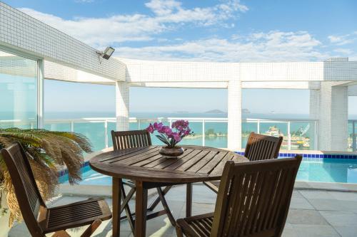 a wooden table with chairs and a table with purple flowers at Golden Tulip Macaé in Macaé