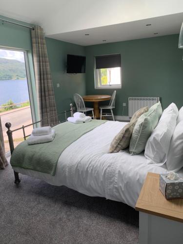 Alt-an Retreat Lodge overlooking loch linnhe في فورت ويليام: غرفة نوم بسرير كبير مع طاولة ونافذة