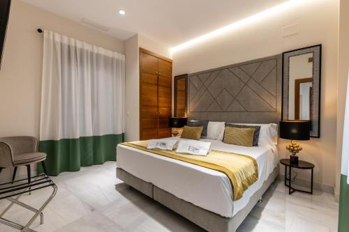 a bedroom with a large bed and a chair at BiBo Suites Real Chancilleria in Granada
