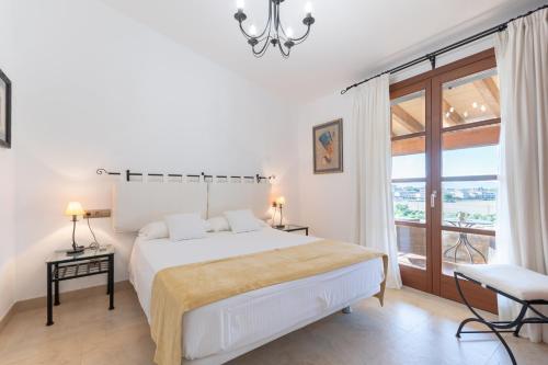 a white bedroom with a bed and a large window at Es Flavo in Sineu