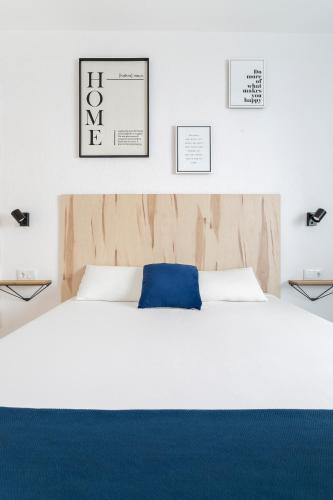 a bedroom with a large white bed with a blue pillow at HB ROOMS - Casa M&J Guest House in Alicante