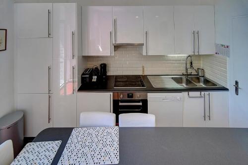 une cuisine avec des armoires blanches et une table et des chaises dans l'établissement IMMOGROOM - Fully equipped -AC- near Palais des Festivals, à Cannes