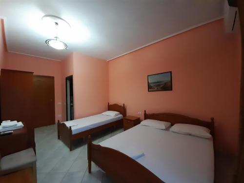 Duas camas num quarto com paredes cor de laranja em Hotel Rossi em Vlorë