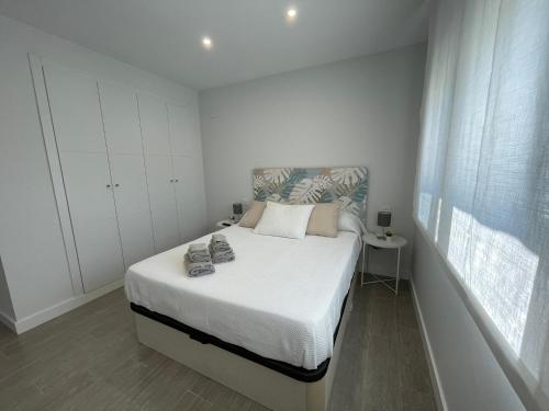 a small white bedroom with a bed and a window at Amazing Duna Beach Seafront Apartament in Torrox