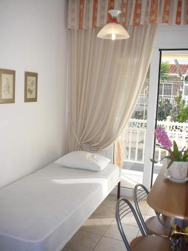 a bedroom with a bed and a window with a balcony at Apartments Juli in Nea Potidaea