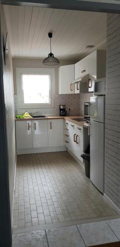 une cuisine avec des armoires blanches et une fenêtre dans l'établissement Appartement spacieux et lumineux Secteur Petit Marché à 5 min a pied de la plage, à Saint-Jean-de-Monts
