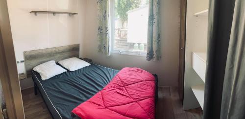 une petite chambre avec un lit avec une couverture rouge dans l'établissement Mobil Home Valras-Plage, à Valras-Plage