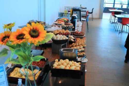 ein Buffet mit Speisen und Blumen in einem Zimmer in der Unterkunft Transamerica Executive Taboao Morumbi in Taboão da Serra