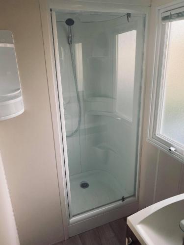 une douche avec une porte vitrée dans une salle de bain dans l'établissement Mobil Home Valras-Plage, à Valras-Plage