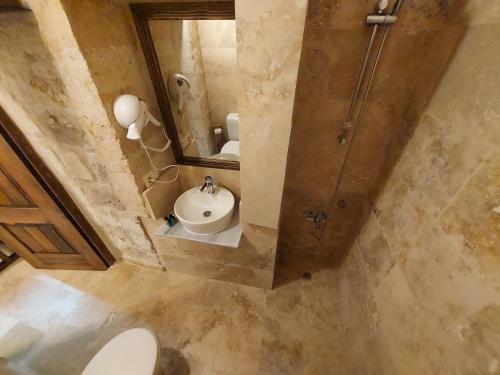 a bathroom with a sink and a toilet and a mirror at ARMEsos Cave Hotel in Urgup